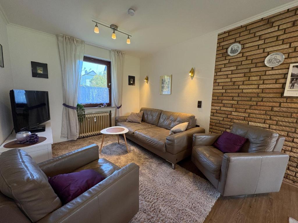 a living room with couches and a brick wall at Ferienwohnung Löffel-Lodge in Heimbach