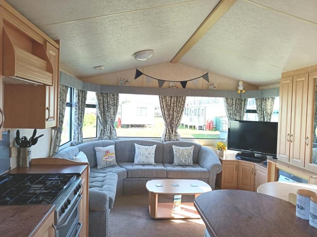 a living room with a couch and a tv in a caravan at VJ Plum a 2 bed 6 berth luxury static caravan, bedding Included, on Coral Beach in Ingoldmells in Ingoldmells