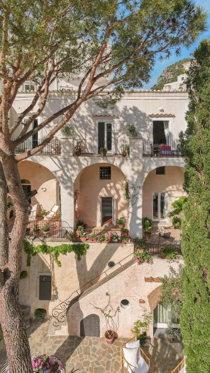 a large white building with balconies and a tree at Casa Sam Positano in Positano