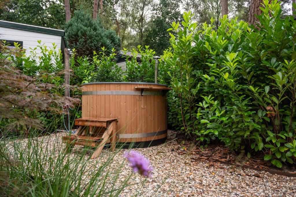 a large wooden tub sitting in a garden at Wild Flower Wellness met privé Sauna en Hottub in prachtige tuin met overkapping in Hoenderloo