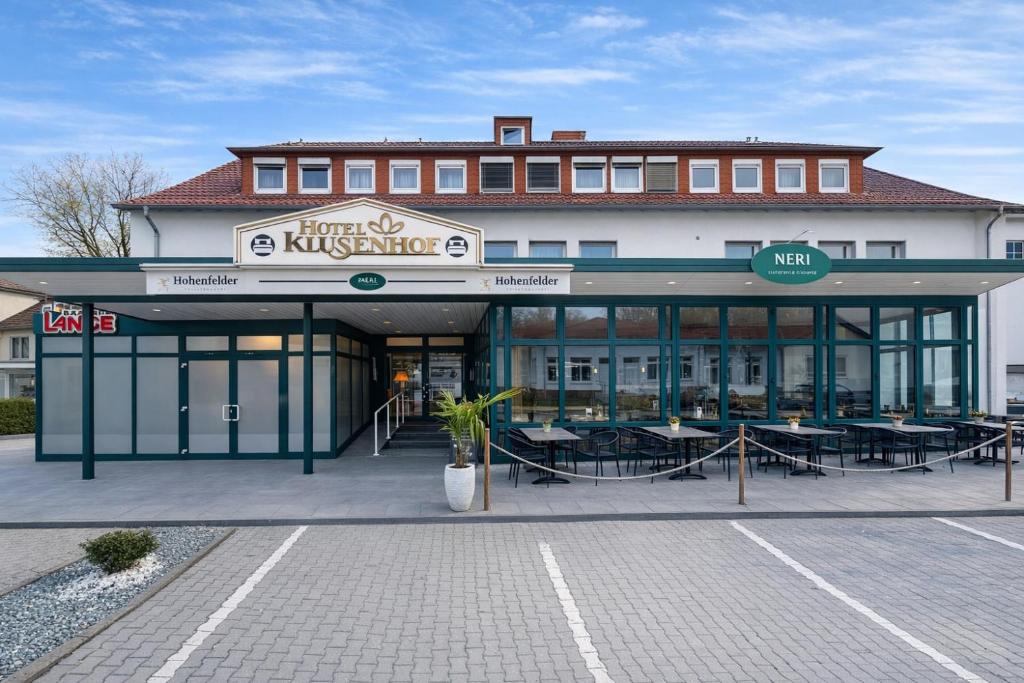 a building with tables and chairs in front of it at Hotel Klusenhof in Lippstadt