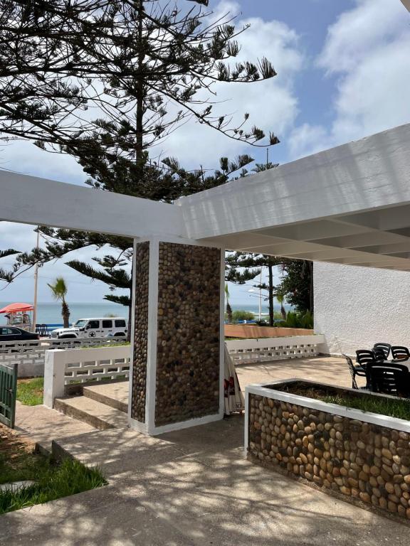 a white pavilion with a stone wall and a tree at Azul Blue House in Sidi Bouzid