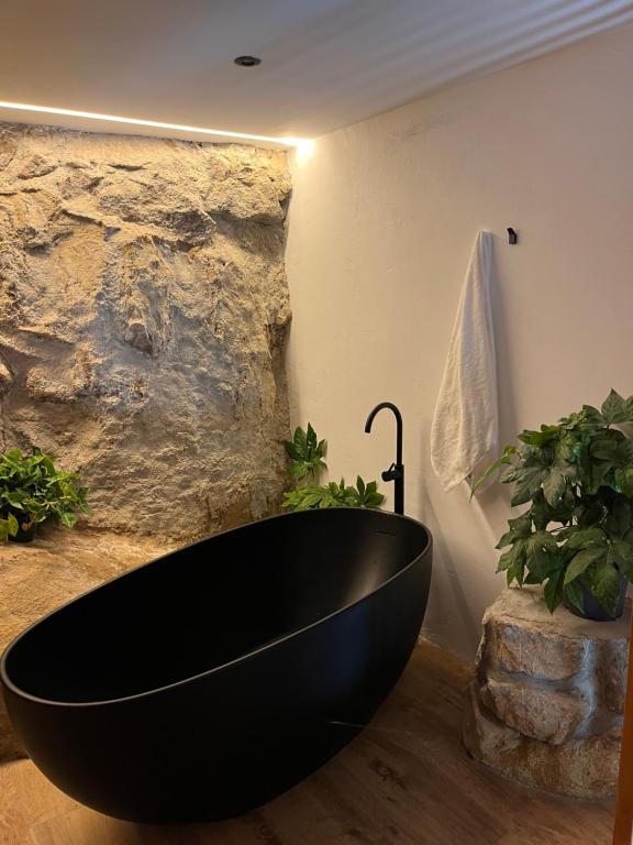 a black bath tub in a bathroom with plants at La Posada de Botavara in Mijares