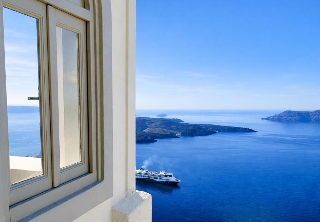 a window with a view of a boat in the water at Yposkafo Suites - Private Studio - Santorini in Fira