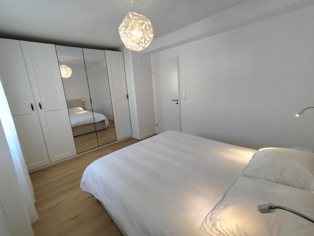 a white bedroom with a bed and a mirror at Chez Mika in Linxe