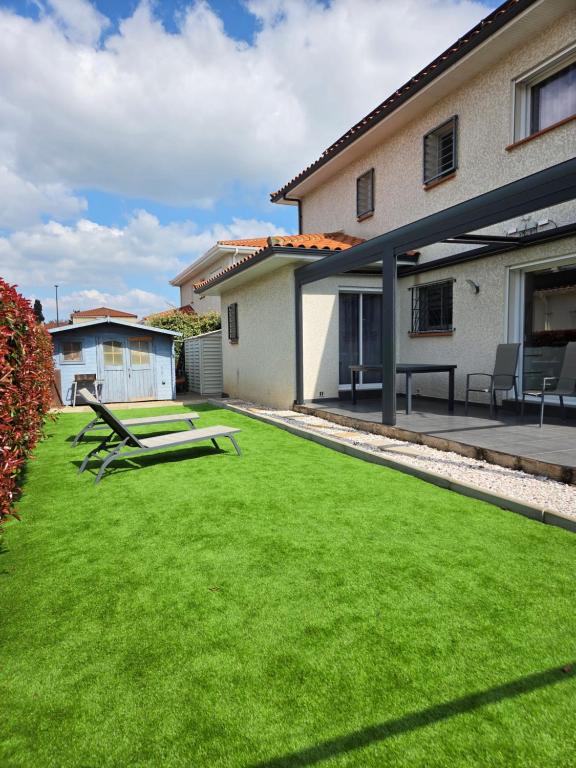 a yard with green grass in front of a house at Chez Titelle in Saint-Laurent-de-la-Salanque