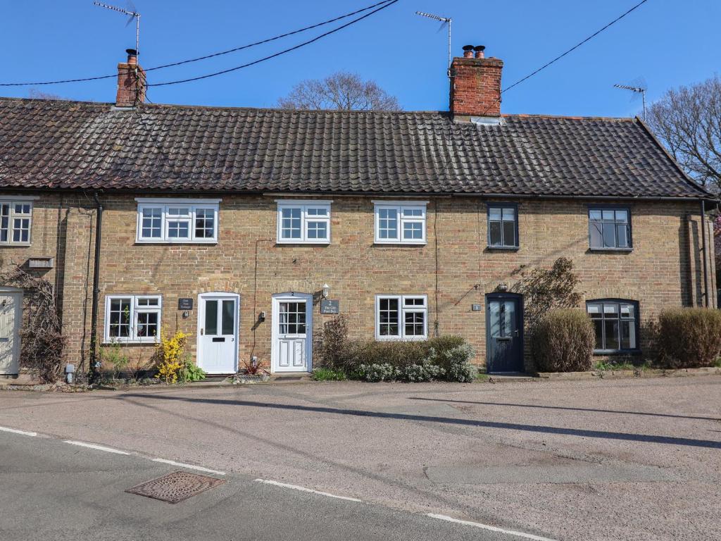 a brick house with white doors on a street at The Old Post Box in Holton