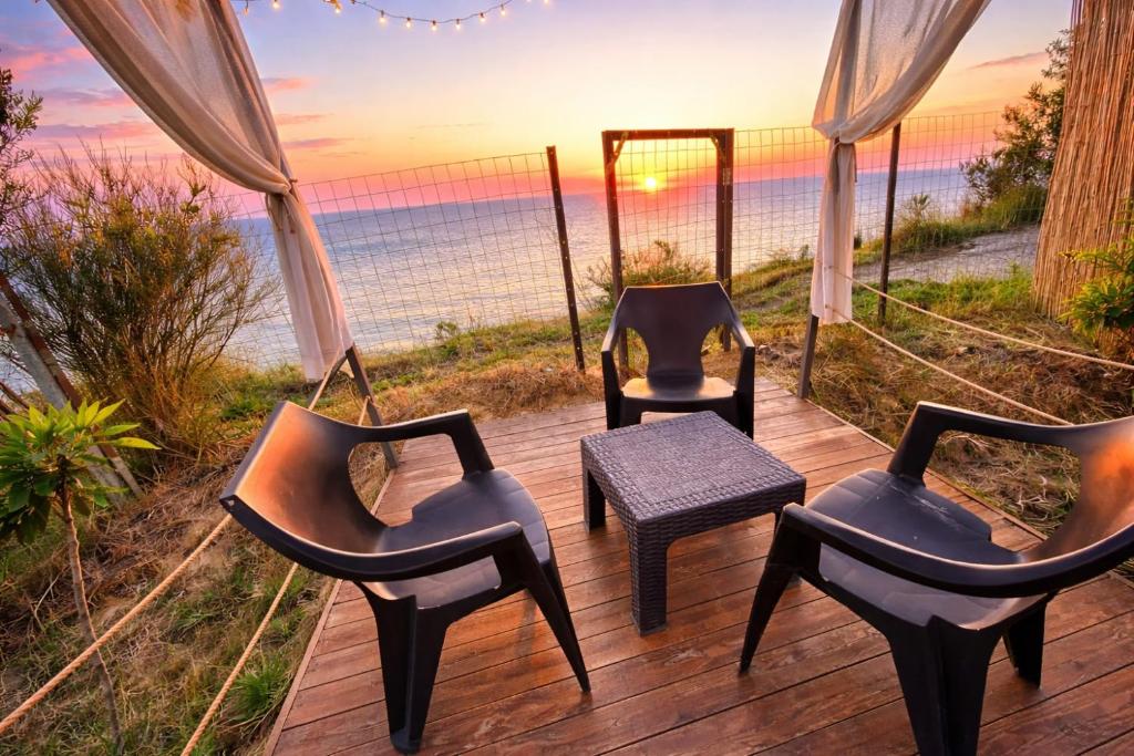three chairs and a table on a deck with the beach at Beus home in Durrës