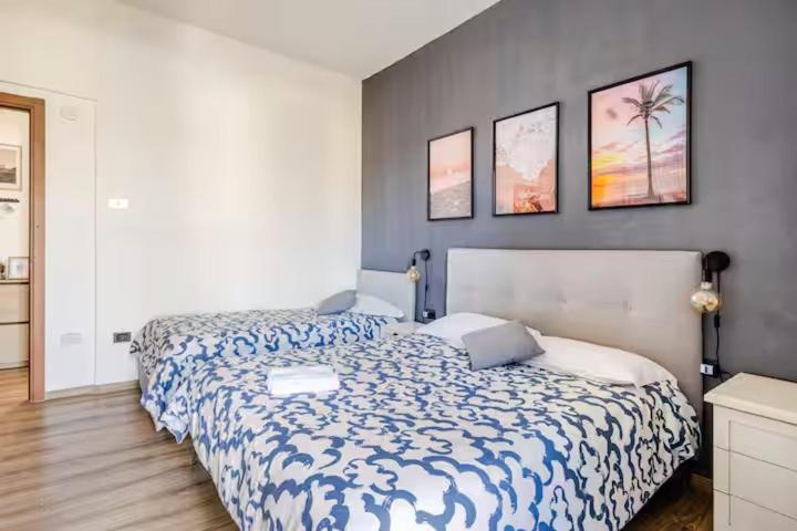a bedroom with two beds and three pictures on the wall at Luminoso Appartamento con Balcone & ParcheggioFree in La Spezia
