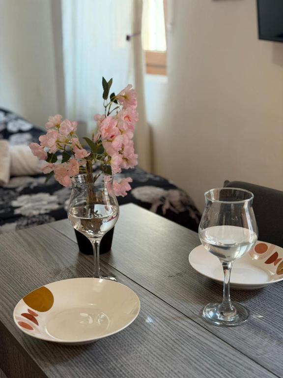 a wooden table with two plates and a vase with flowers at Grazia's Heaven in Trezzo sullʼAdda