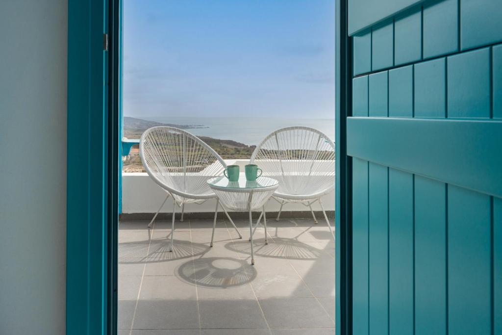a table and chairs on a balcony with a view of the ocean at Silver Lining in Akrotiri