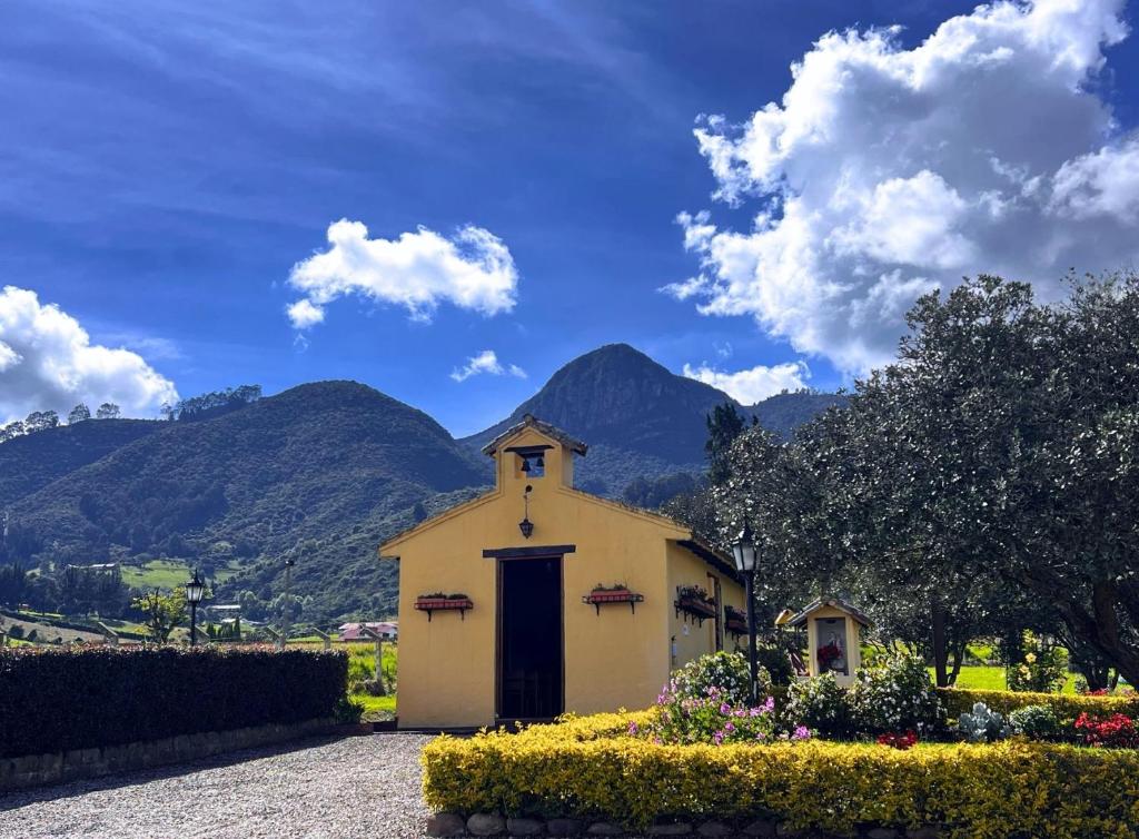 a small yellow church with mountains in the background at La Franchesca Hotel Boutique in Tabio
