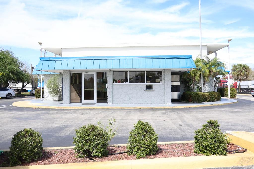 a building with a blue awning in a parking lot at Crossroads Inn in Fort Pierce
