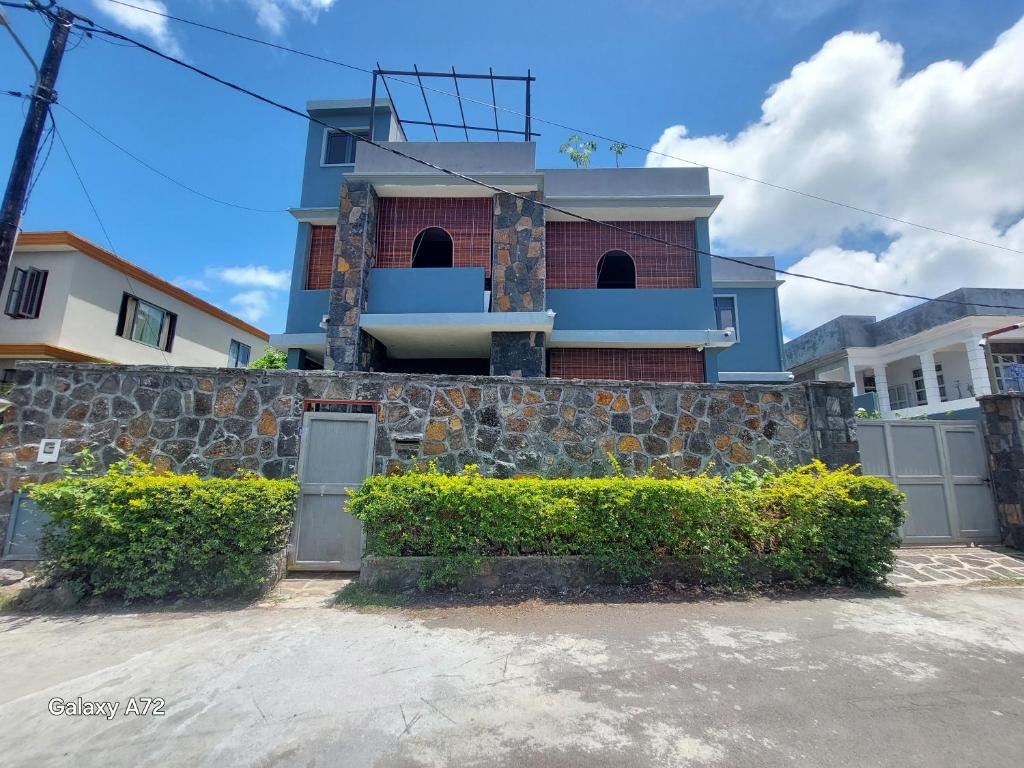 a house with a stone wall and a fence at Appartement Le Cap in Cap Malheureux