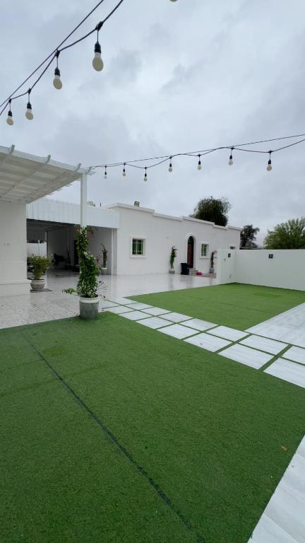a courtyard with green grass and a white building at Ghala Farm in Adh Dhayd