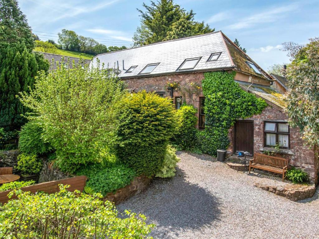 a brick cottage with a bench in the garden at Allerford- Ukc4920 in Timberscombe