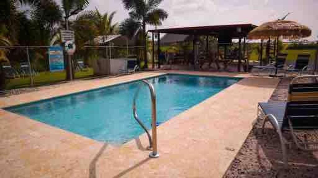 a large swimming pool with an umbrella and chairs at Cozy 2BR Cabin for 5 with Pool in Cabo Rojo