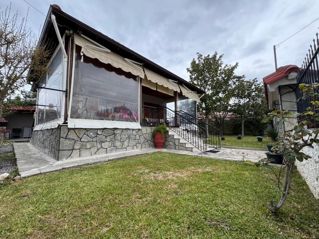 a stone house with a large window and a yard at Pansedon House by the sea in Nea Kallikrateia