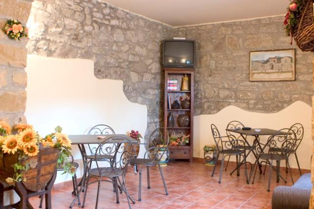 a room with tables and chairs and a stone wall at Il Baglio di Nonna Clelia in Polizzi Generosa