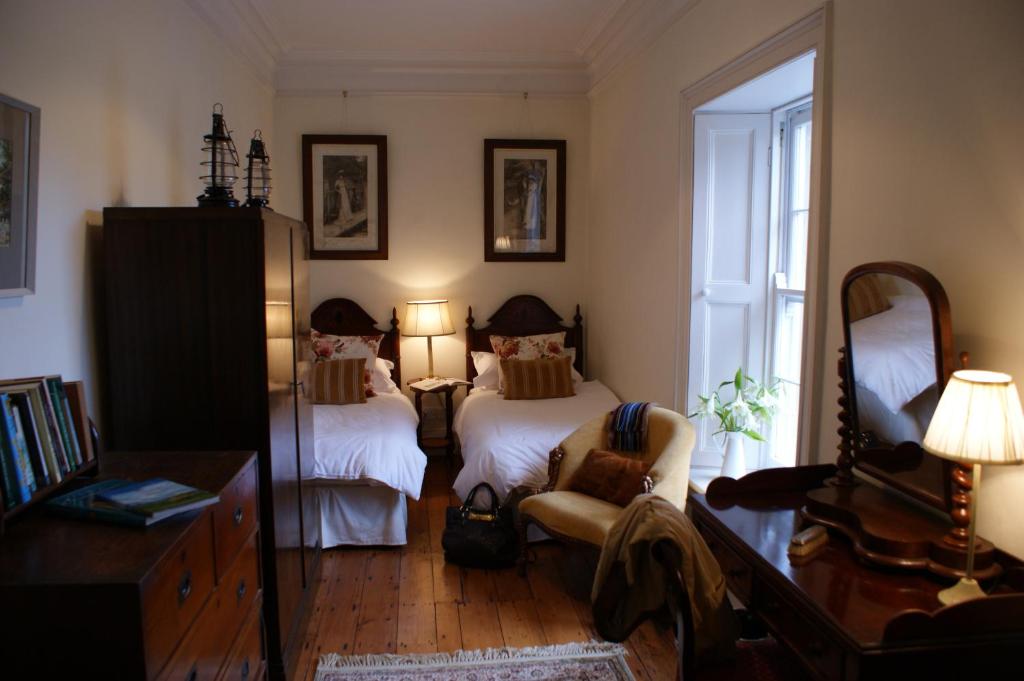 1 dormitorio con 2 camas, silla y espejo en Inchiquin House en Corrofin