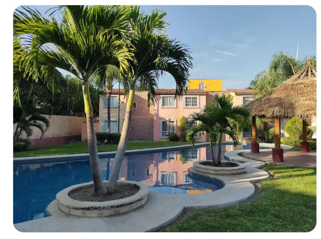 a resort with palm trees and a swimming pool at Casa completa equipada para cualquier ocasión in Tezoyuca