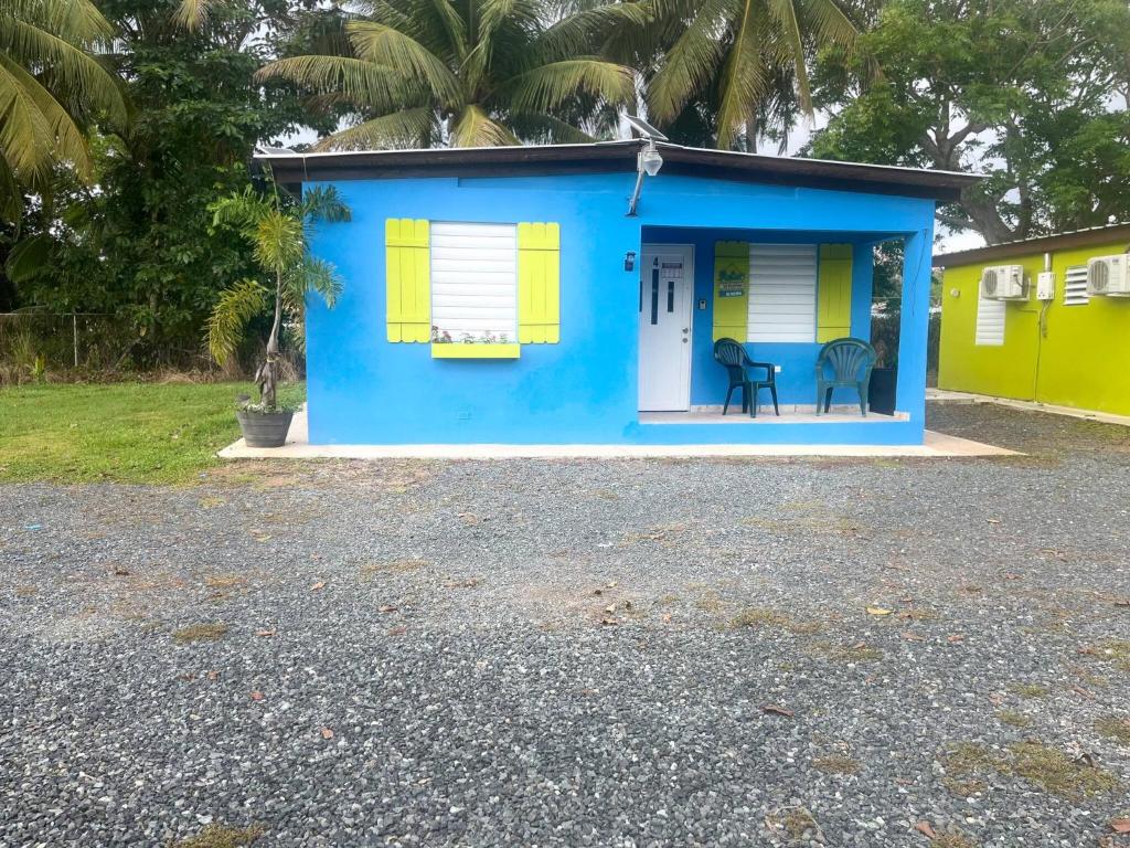 a blue and yellow house with a chair in front at Cozy 2BR Cabin with Pool in Cabo Rojo in Cabo Rojo