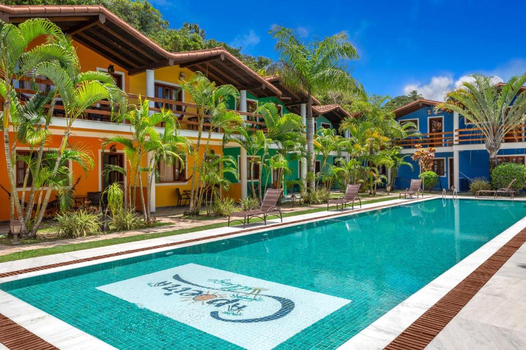 a swimming pool in front of a building with a resort at Capoeira Village in Porto Seguro