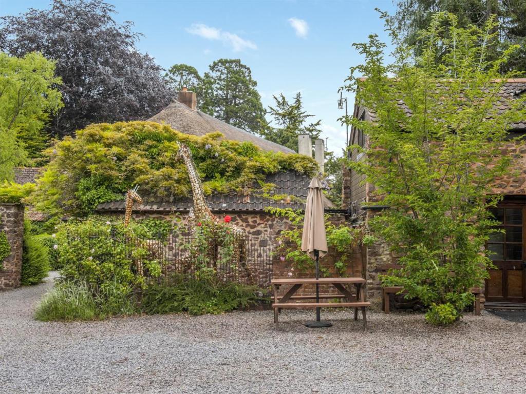 an umbrella and a bench in front of a building at Luccombe- Ukc4919 in Timberscombe