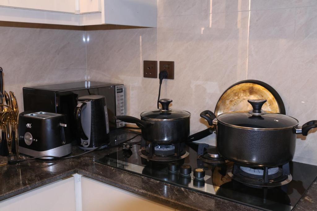 two pots and pans on a stove in a kitchen at Designer Den two Bed apartment opposite to giga mall in Islamabad