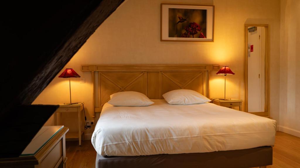 a bedroom with a white bed with two lamps at Logis Hôtel L'Orée des Charmes et son restaurant L'évYdenCe in Blaisy-Bas