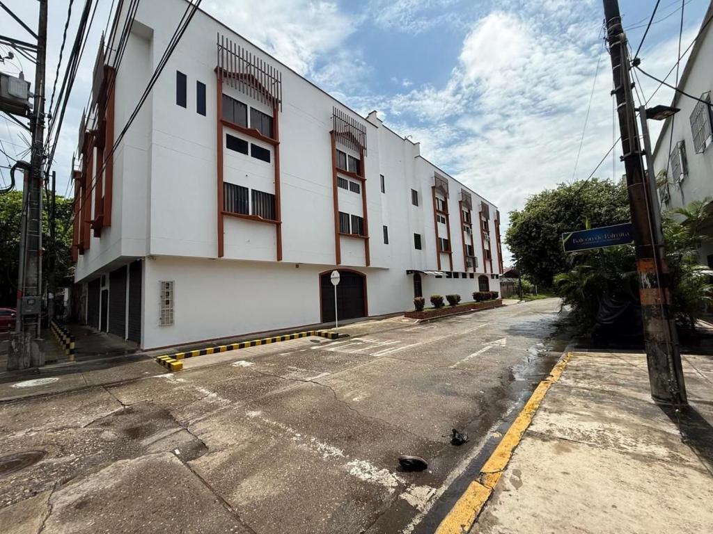 an empty street in front of a white building at Operadora Stay - Edificio Puerto Living in Barrancabermeja