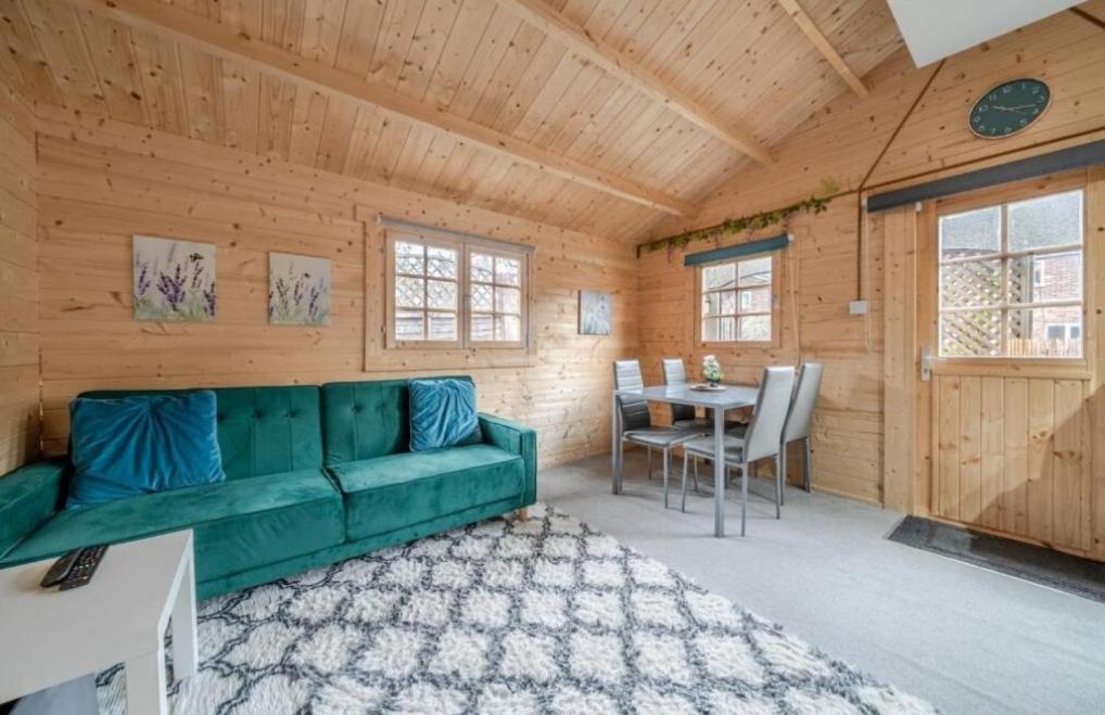 a living room with a green couch and a table at The Cosy Cabin in Old Windsor