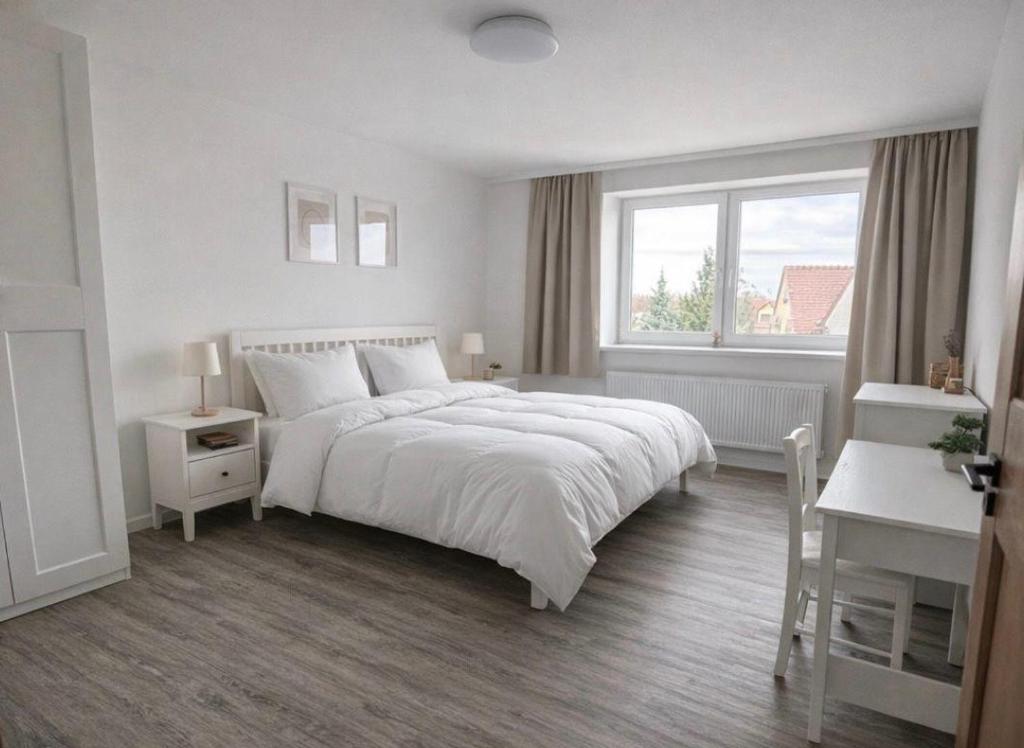a white bedroom with a large bed and a window at Apartmány Bozen Lednice in Lednice