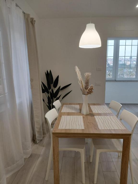 a dining room table with white chairs and a potted plant at b&b Il Margonico in Potenza