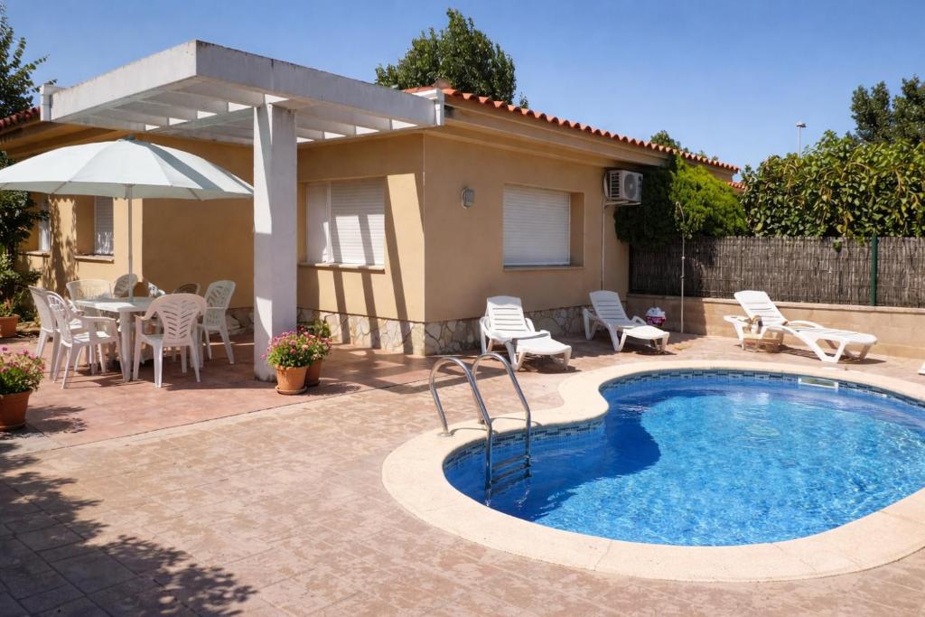 a swimming pool with chairs and a table and an umbrella at Casa Marga - " Pet friendly - Piscina Privada - Playa - BBQ - Parking - Delta de l'Ebre - Riumar" in Riumar
