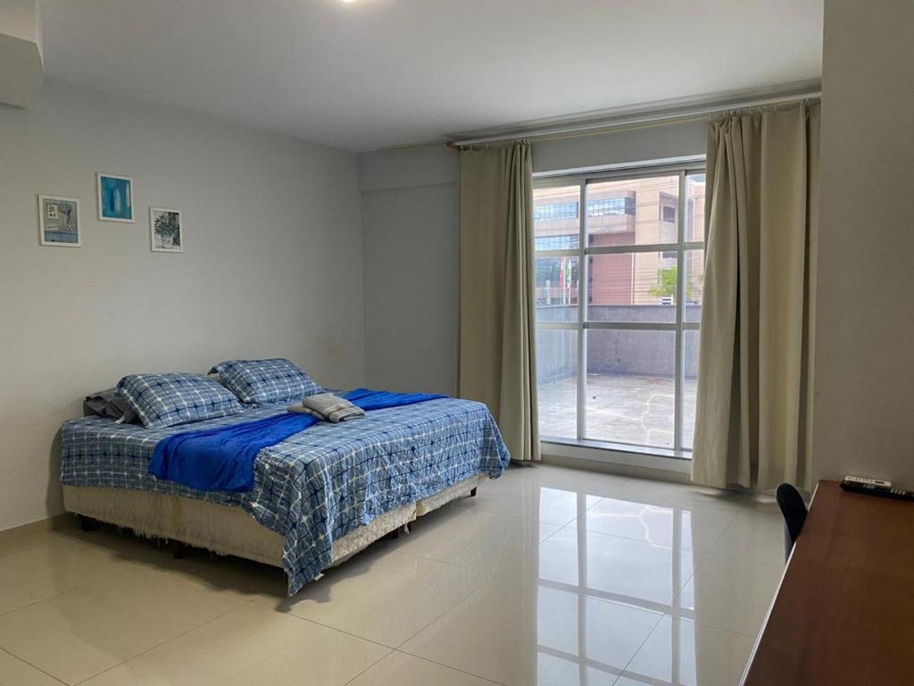 a bedroom with a bed and a large window at 115 - Saint Sebastian Flat in Jaraguá do Sul