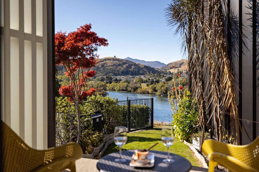 a table with wine glasses and a view of a river at Haven on the Lake Front in Frankton