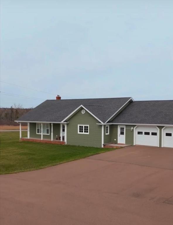 a green house with a gray roof and a driveway at Small Town Bound Inn in Vernon River