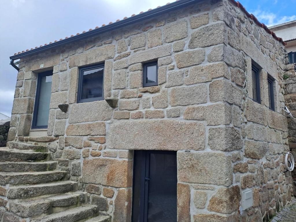 a stone building with a black door and stairs at Casa da Figueira in Aguiar da Beira