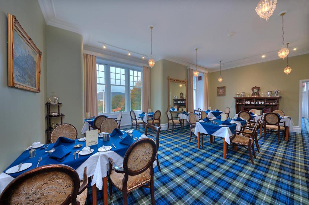 uma sala de jantar com mesas e cadeiras azuis em Falls of Lora Hotel em Oban