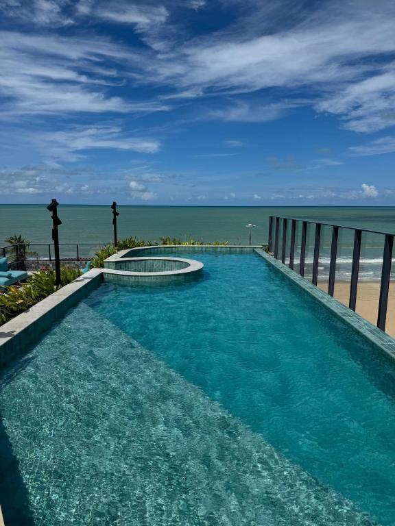 a swimming pool with the ocean in the background at Garden Haus - Flat beira mar in João Pessoa