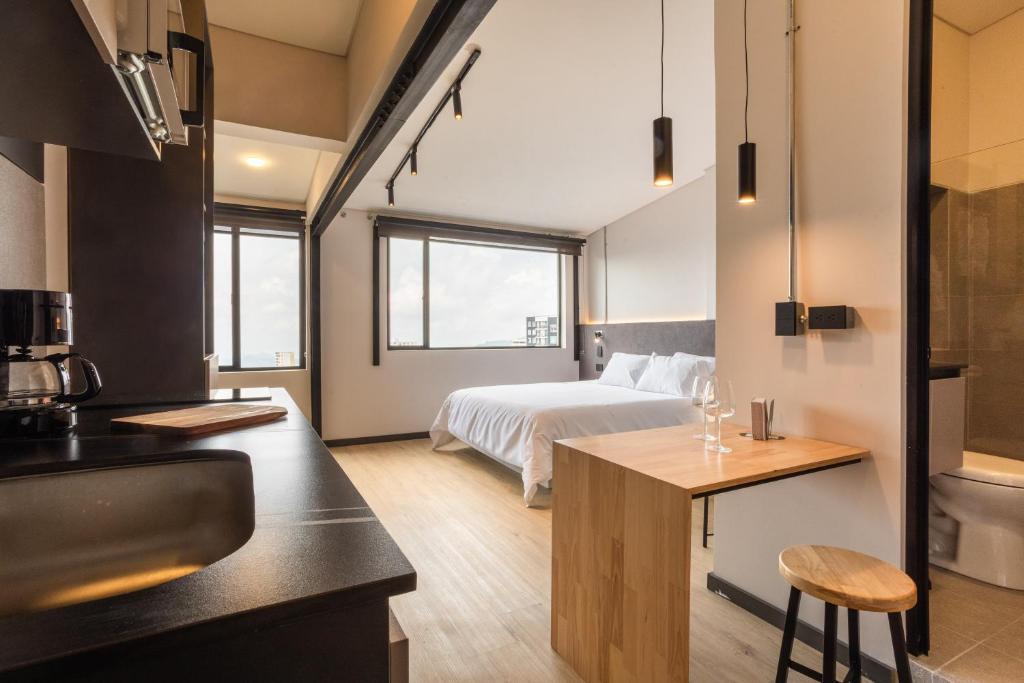 a bedroom with a bed and a kitchen with a sink at Break Estudios Manizales in Manizales