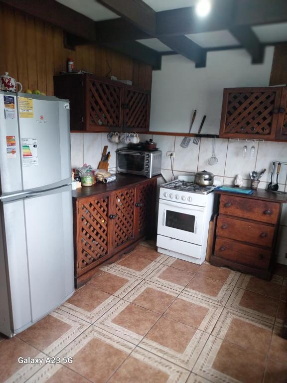 a kitchen with a white refrigerator and a stove at Casa Halcon de Lagunitas in Puerto Montt