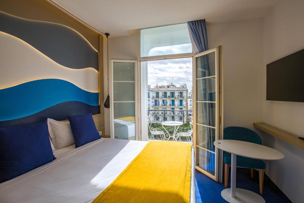 a hotel room with a bed and a balcony at Hotel Carlton in Tunis