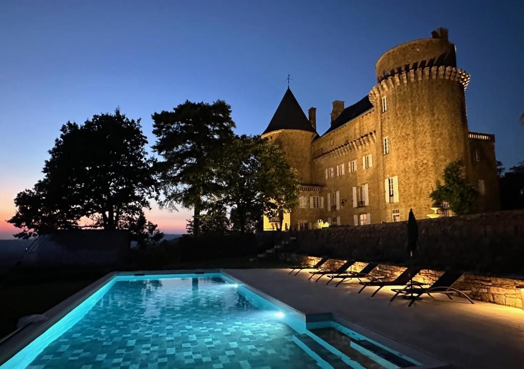 a swimming pool in front of a castle at night at Château Blanat in Saint-Michel-de-Bannières