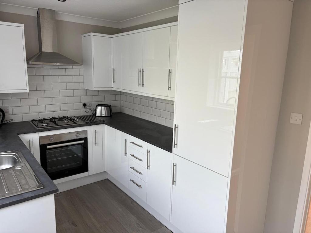 a white kitchen with white cabinets and a sink at New Forest Home in Hordle