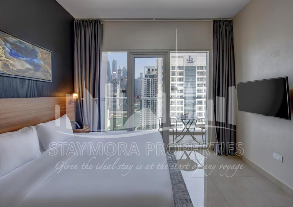 a hotel room with a bed and a large window at Staymora Suites in Dubai