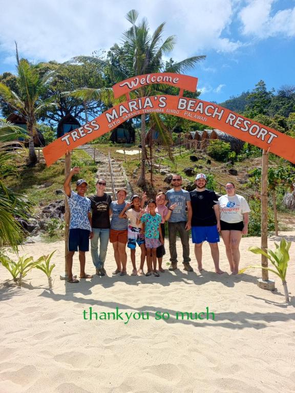 a group of people standing under a sign on the beach at Tress Maria's beach resort in Brother Islands