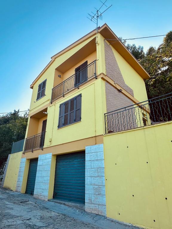 a yellow building with two garage doors and a balcony at Villa sul mare di Cupra in Cupra Marittima