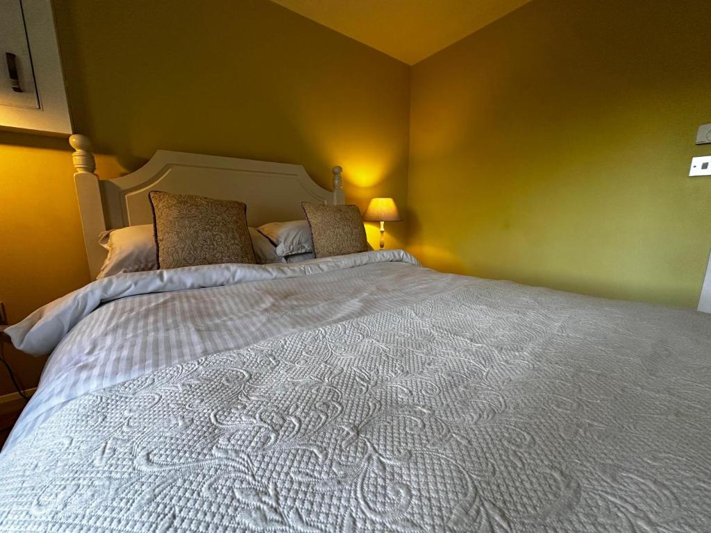a bedroom with a large white bed with two pillows at The Potting Cottage in Tydd Saint Giles